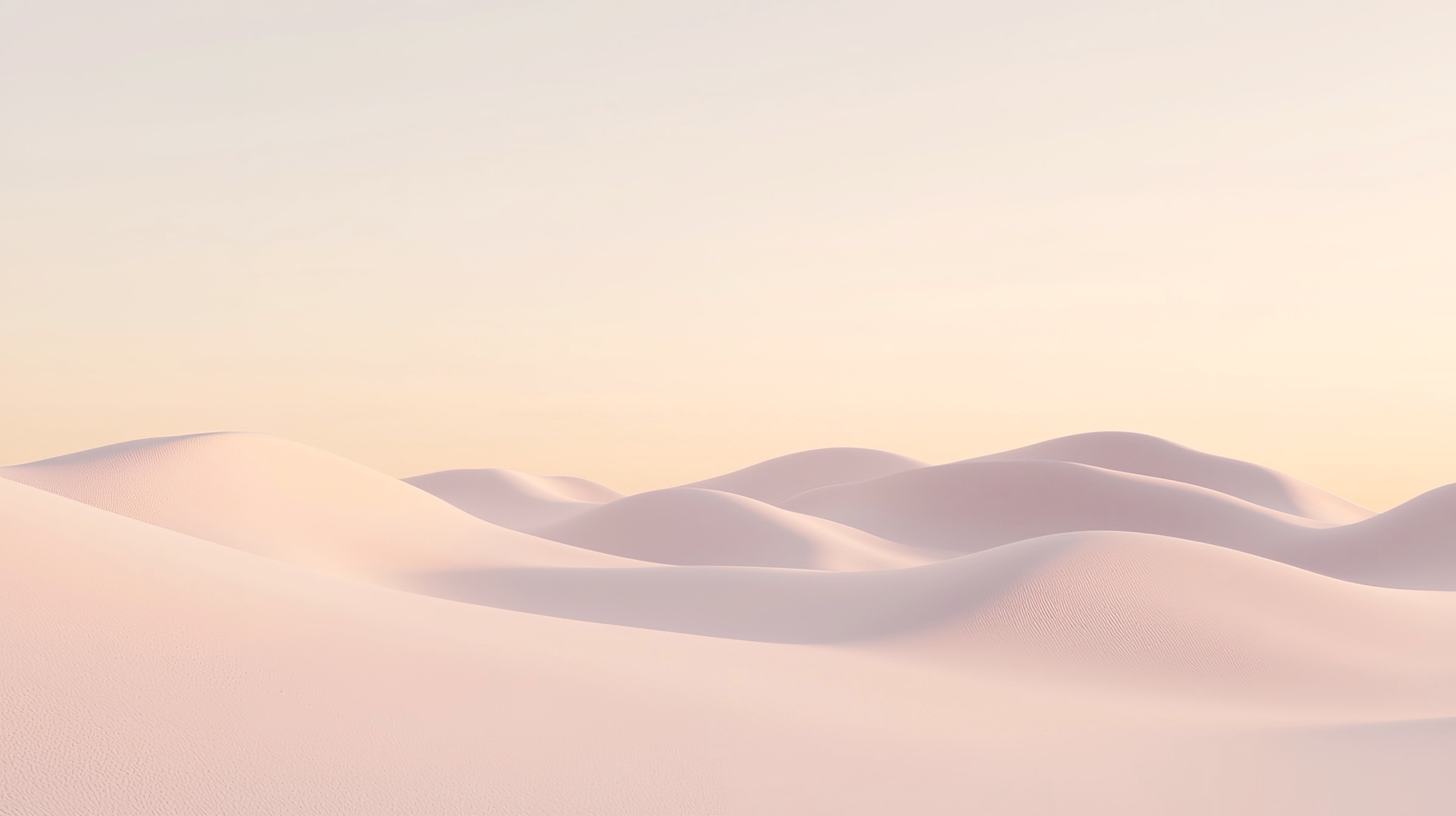 Dunes de sable pâle aux reflets rosés sous un ciel crème