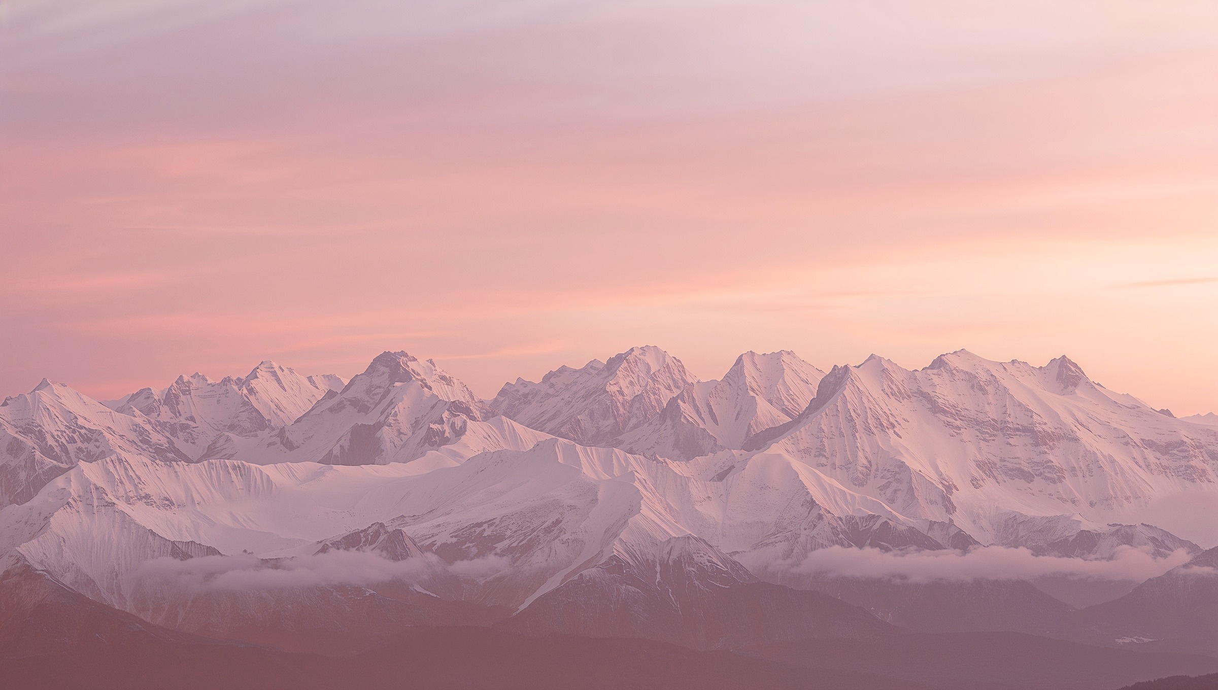 Chaîne de montagnes enneigées sous un ciel rose au couchant
